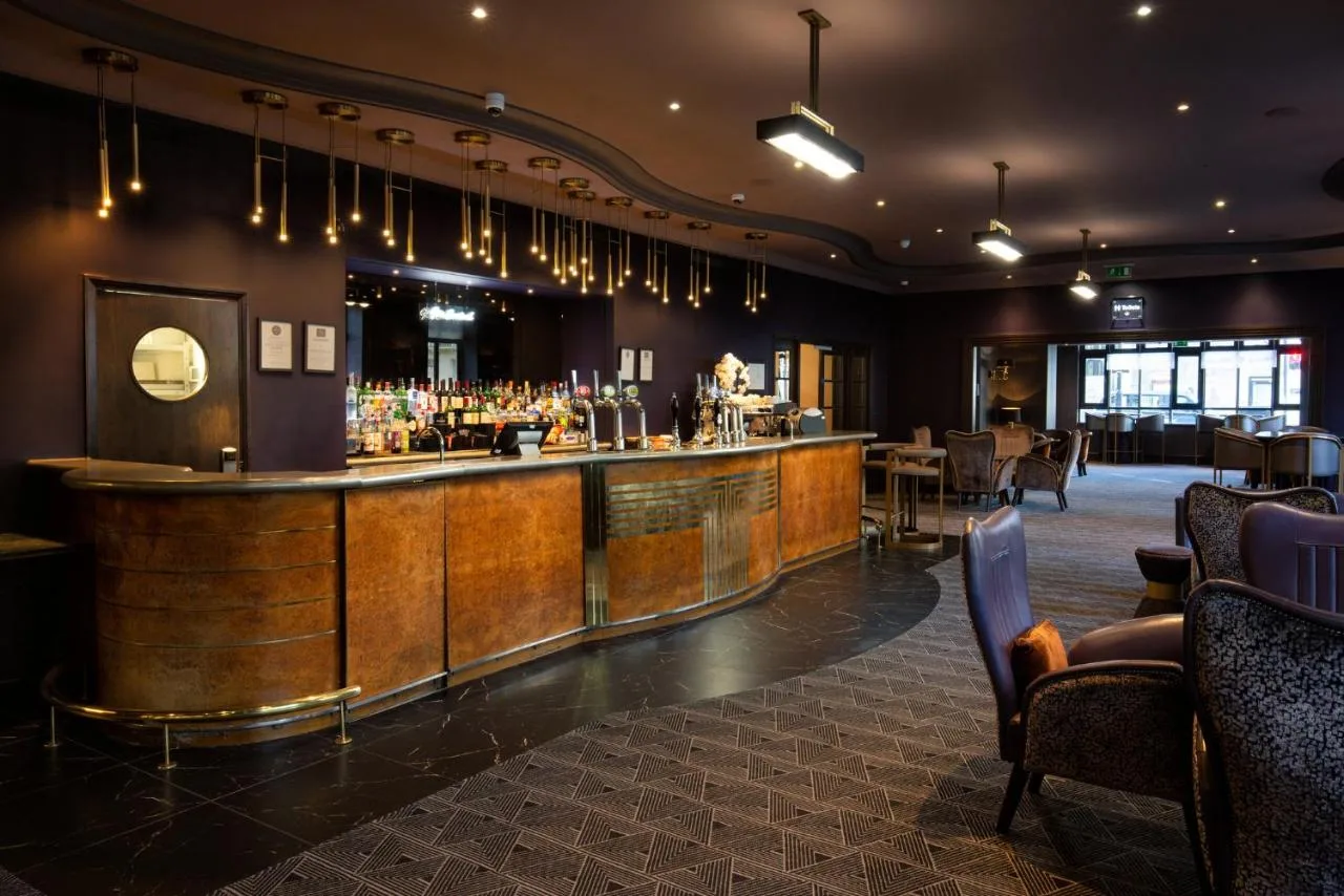 a bar in a restaurant with a counter and chairs at Tavistock Hotel in London