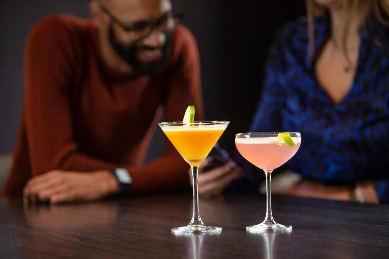a man and a woman sitting at a table with two cocktails at Tavistock Hotel in London
